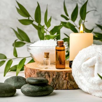 beauty treatment items for spa procedures on white wooden table. massage stones, essential oils and sea salt. copy space